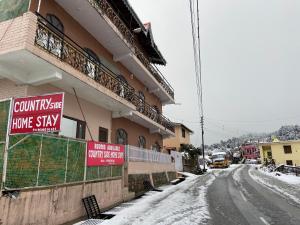 ein Gebäude auf einer verschneiten Straße mit Schildern darauf in der Unterkunft Country Side Home Stay in Rānīkhet