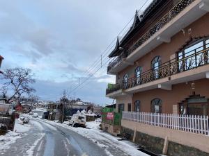 a snow covered street next to a building at Country Side Home Stay in Rānīkhet