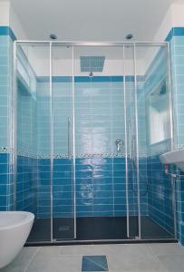 a blue tiled bathroom with a shower and a sink at The little tower of Minuta in Scala