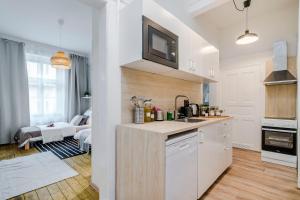 uma cozinha com armários brancos e uma sala de estar em Spacious APT in Prague Center by Michal&Friends em Praga