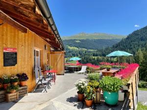 ein Gebäude mit Tischen, Stühlen und Blumen in Töpfen in der Unterkunft BnB Guesthouse Lusi in Frauenkirch