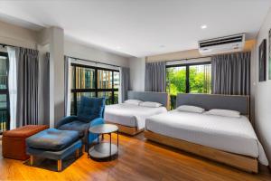 a hotel room with two beds and a chair at Nest by Sangob in Bangkok