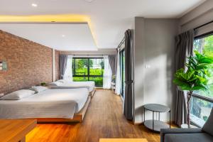 a bedroom with three beds and a brick wall at Nest by Sangob in Bangkok
