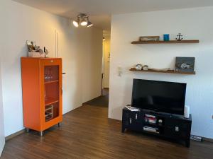 a living room with a tv and an orange cabinet at Business-Apartment Boltentor in Emden