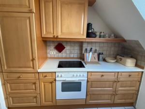 a kitchen with a stove and wooden cabinets at Business-Apartment Boltentor in Emden +11 photos