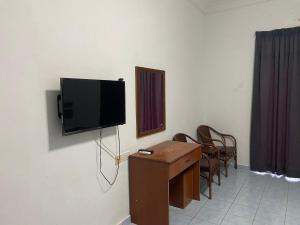 a tv on a wall with a table and chairs at SURIA BEACH RESORT Pangkor in Pangkor