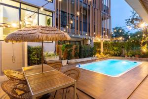 una mesa con sombrilla junto a la piscina en Nest by Sangob, en Bangkok