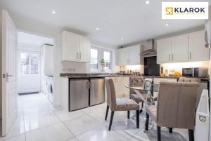 a kitchen with white cabinets and a table and chairs at LONG STAYS 30pct OFF - Spacious 4Bed - Sports Channels - Parking By Klarok Short Lets & Serviced Accommodation in Peterborough