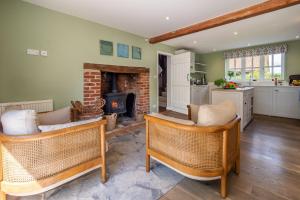 a living room with two chairs and a fireplace at Foxhole Cottage in Stowmarket