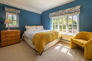 a bedroom with blue walls and a bed and a chair at Foxhole Cottage in Stowmarket