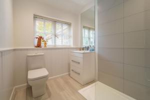 a white bathroom with a toilet and a sink at Foxhole Cottage in Stowmarket