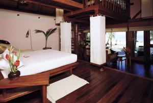 a bedroom with a bed and a living room at Sandoway Resort in Ngapali