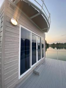 a wooden deck with a large window on the water at Blue Village in Savigliano