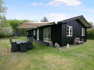 una casa negra con un perro sentado fuera de ella en Newly Renovated Cottage With Love And Soul, en Kirke-Hyllinge