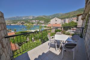 a balcony with a table and chairs and a view of the water at Kazanegra Exclusive Apartments in Sveti Stefan