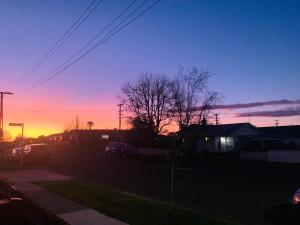 a sunset in a yard with cars parked on the street at Auckland Homestay-Ensuite Room, near Airport,Free Parking in Auckland