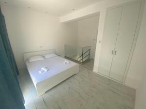 a white bedroom with a bed and a mirror at 1-bedroom duplex 100m by the sea in Limassol
