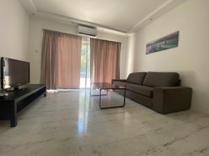a living room with a couch and a television at 1-bedroom duplex 100m by the sea in Limassol