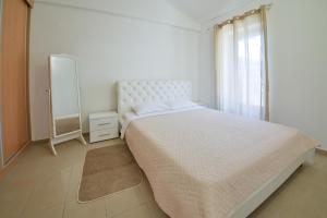 a white bedroom with a large bed and a mirror at Kazanegra Exclusive Apartments in Sveti Stefan