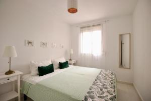 a white bedroom with a large bed with green pillows at Sweet Home Apartaments in El Médano