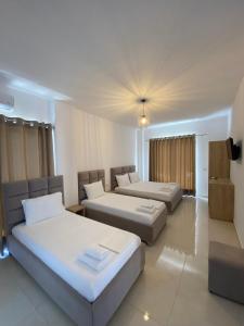 Habitación de hotel con 2 camas y TV en J&B Hotel en Ksamil