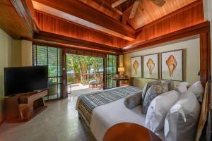 Centara Grand Beach Resort & Villas Krabi في شاطيء آونانغ: غرفة نوم بسرير وتلفزيون بشاشة مسطحة