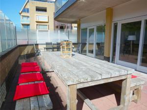 een houten picknicktafel met rode kussens op een patio bij Wijde Blick XL aan Zee in Callantsoog