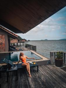 une femme assise sur une table à côté d'une piscine dans l'établissement Vedana Lagoon Resort & Spa, à Hue