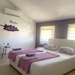 1 dormitorio con 1 cama grande y toallas. en Purple rooms, en Mostar