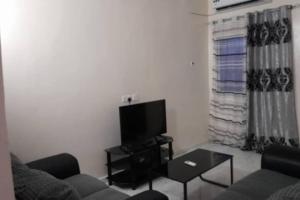 a living room with a couch and a flat screen tv at Bambino Guest House in Brikama