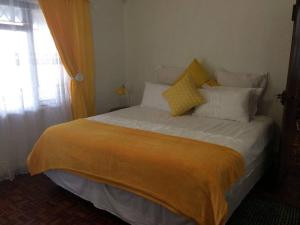 een slaapkamer met een groot bed met gele en witte kussens bij The Holiday Home on the Beach in Port Shepstone