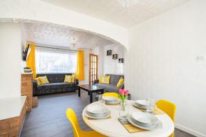a living room with a white table and yellow chairs at Cosy House #Lea Hall Train Station #BHX #NEC #NIA in Birmingham