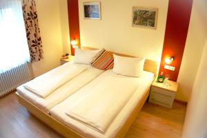 a bedroom with a large bed with white sheets at Gasthof zum Löwen in Gößweinstein