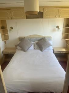 a bed with white sheets and pillows in a room at Central Ingoldmells, Seaview 6 berth in Ingoldmells