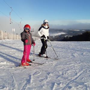 uma mulher e uma criança em esquis na neve em CHARMANT CHALET dans les monts du Forez em Le Fayt