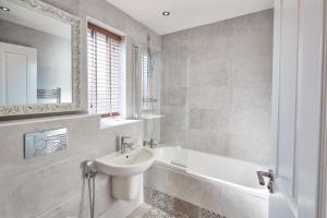 a bathroom with a sink and a tub and a mirror at Host & Stay - Greenfinch Road in Coventry