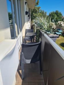 une rangée de chaises sur un balcon avec des plantes dans l'établissement Bel appartement tout proche du Mont st Michel, à Pontorson