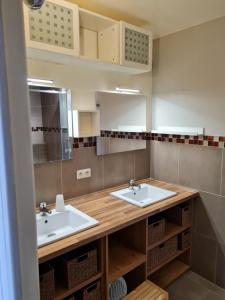 a bathroom with two sinks and a counter with baskets at Bel appartement tout proche du Mont st Michel in Pontorson