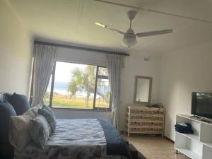 a bedroom with a bed and a window and a television at The Beach House in Port Shepstone