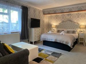 a bedroom with a bed and a tv and a couch at The Paddocks Hotel in Symonds Yat