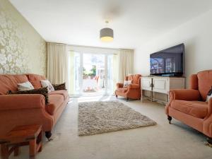 a living room with orange furniture and a flat screen tv at East Shore Way - Portsmouth in Southsea