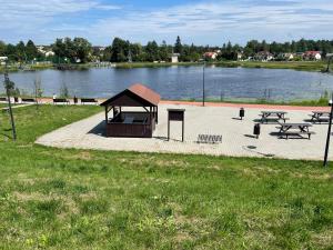 a park with a playground and picnic tables next to a lake at Hostel ELDORADO in Końskie