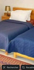 a bed with a blue comforter on top of it at Residence Tozeur Almadina in Tozeur