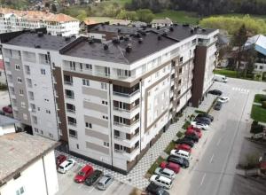 an apartment building with cars parked in a parking lot at Apartman Srna Pale in Pale