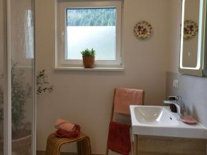 ein Bad mit einem Waschbecken und einem Fenster in der Unterkunft TYROL PURElife Lodges in Sankt Jakob in Defereggen