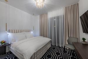 a bedroom with a bed and a chair and a chandelier at Hotel ZEMPLEN in Michalovce