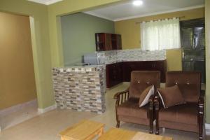 a living room with two chairs and a kitchen at Snow Valley Cottages in Kasese