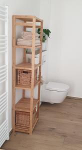 a bathroom with a wooden shelf with baskets and a toilet at Ferienwohnung Jeannette I in Hasselfelde