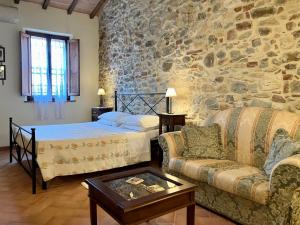a bedroom with a stone wall with a bed and a couch at Casina di Rosa in Civitella Marittima