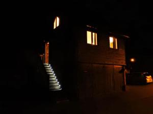uma casa à noite com escadas que levam a uma porta em The Studio, Upper House Farm, Crickhowell. em Crickhowell